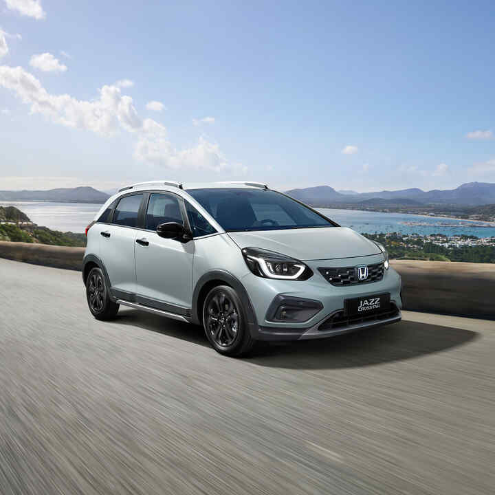 Přední 3/4 pohled na model Honda Jazz Crosstar jedoucího na silnici u pobřeží