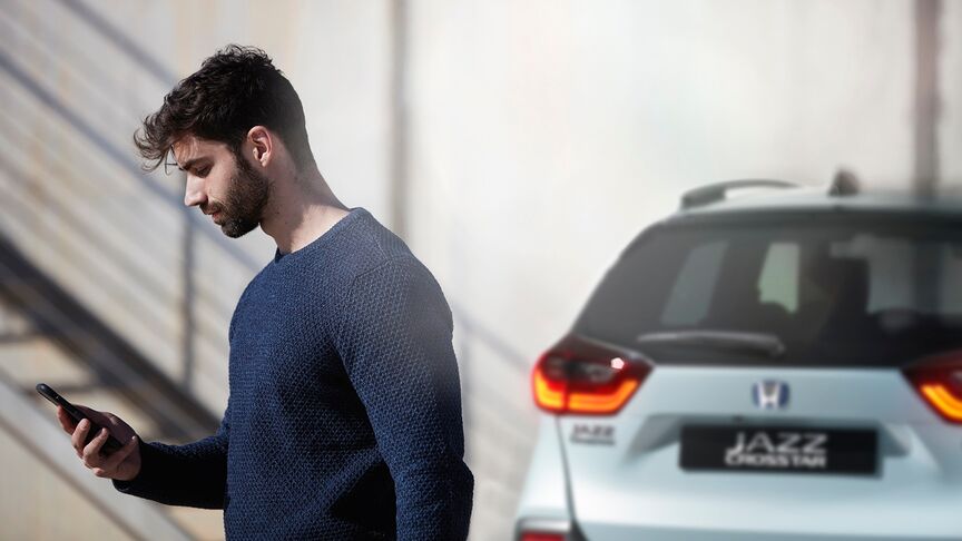 Dáma stojící vedle bílého vozidla Honda e používající aplikaci My Honda+