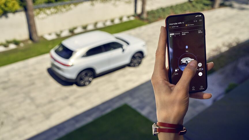 Dáma stojící vedle bílého vozidla Honda e používající aplikaci My Honda+