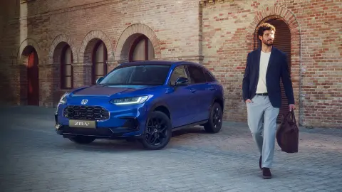 Muž procházející kolem vozu ZR-V Hybrid SUV zaparkovaného ve městě