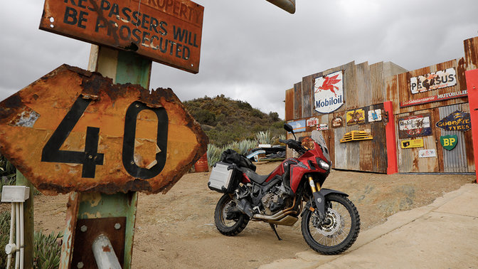 Motocykl Honda CRF1000L Africa Twin zaparkovaný u čerpací stanice.