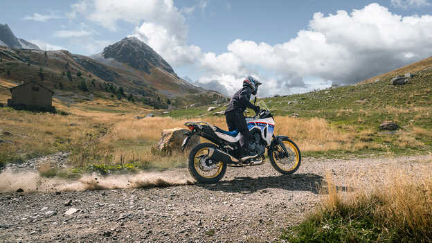 Transalp, dynamický snímek zezadu, s jezdcem, na štěrku